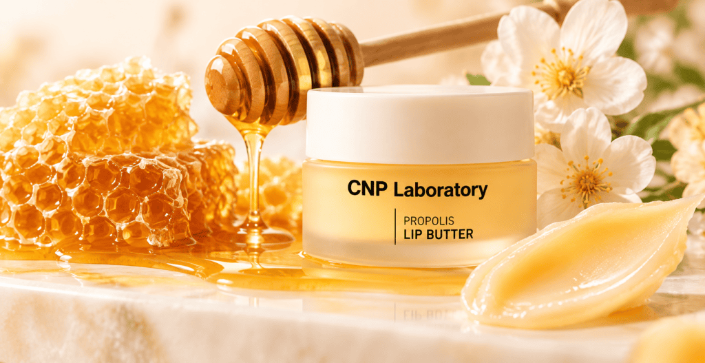 CNP Laboratory Propolis Lip Butter surrounded by golden honey, honeycomb, white flowers, and a honey dipper, highlighting Korean lip care.